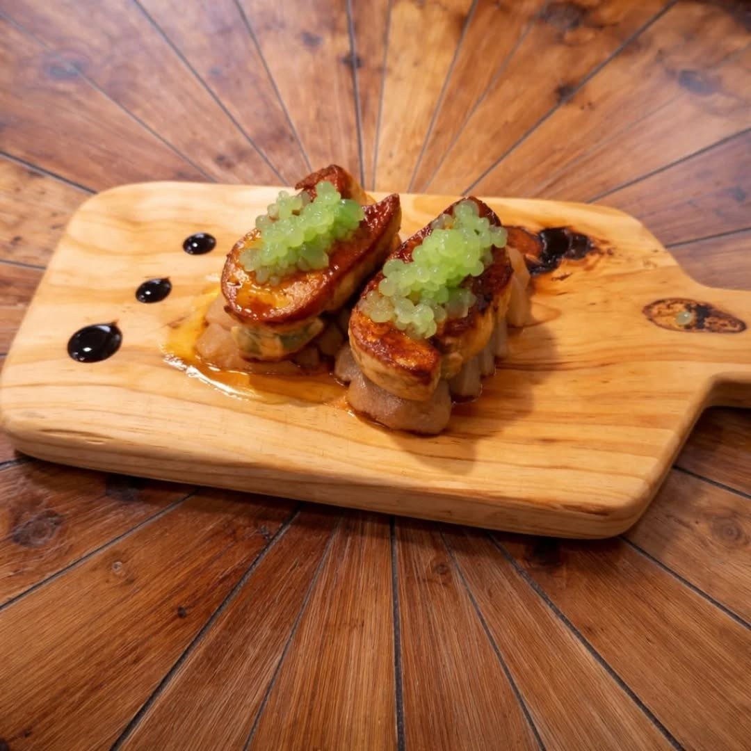 Duas tostas com foie gras e pêra em cubos, numa tábua de madeira