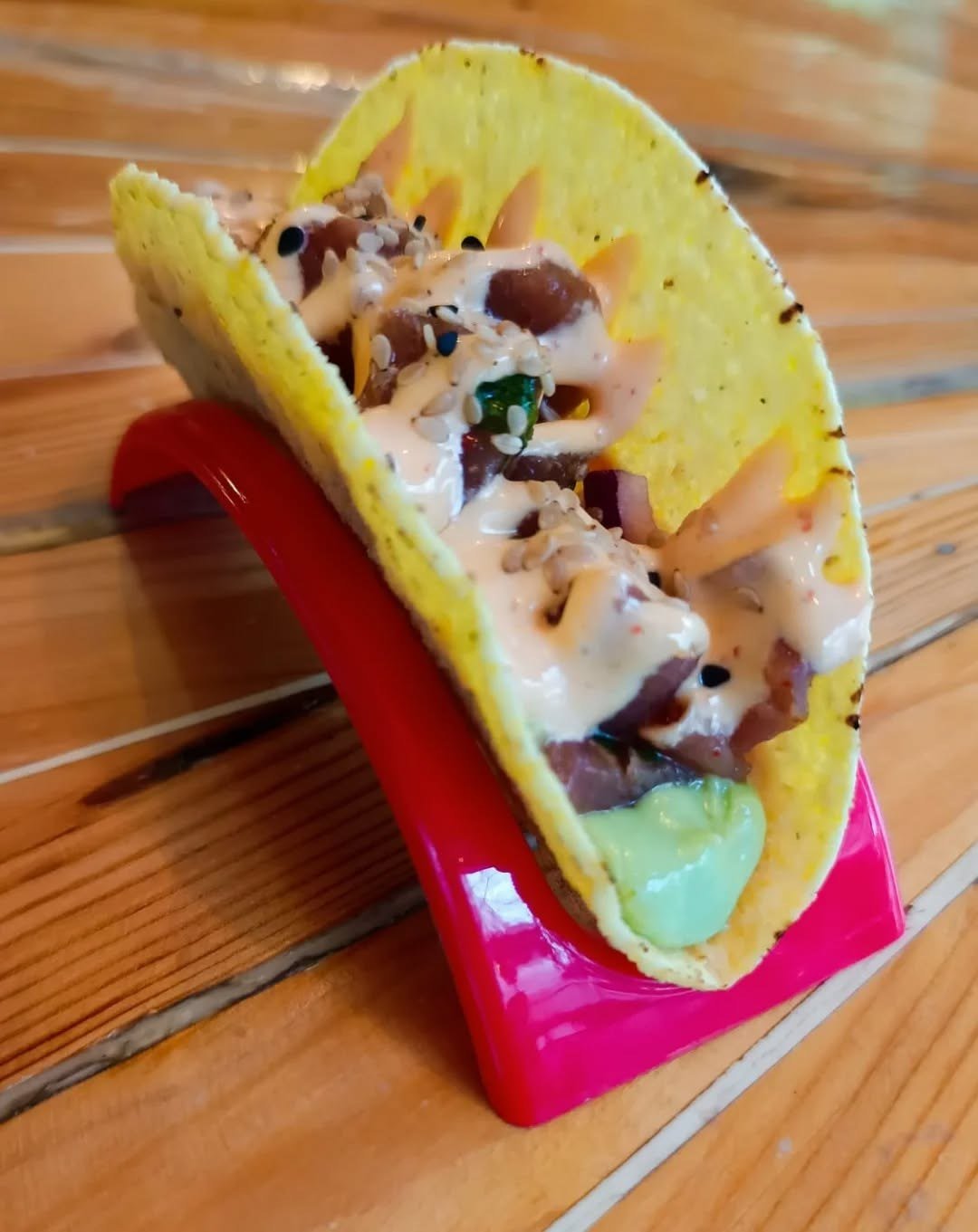 Taco recheado com atum e molho claro, num suporte vermelho